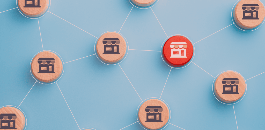 A group of wooden circles, each with a building printed on top, connect with each other. Set against a blue background. Represents the concept of finding the right franchise marketing agency.