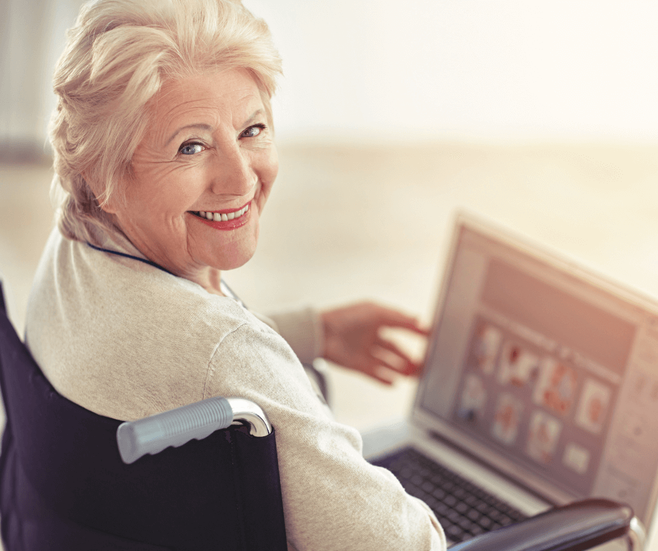 An older white woman in a wheelchair points to a laptop in her lap while smiling at the audience. She represents the concept of "Senior Living SEO."