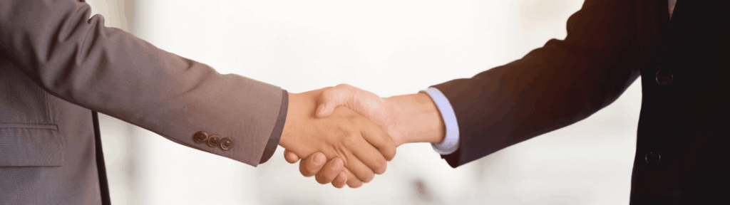 Two people shake hands in a professional setting.